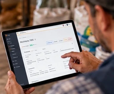 Una persona sostiene una tablet con la pantalla de un movimiento de inventario, en una bodega